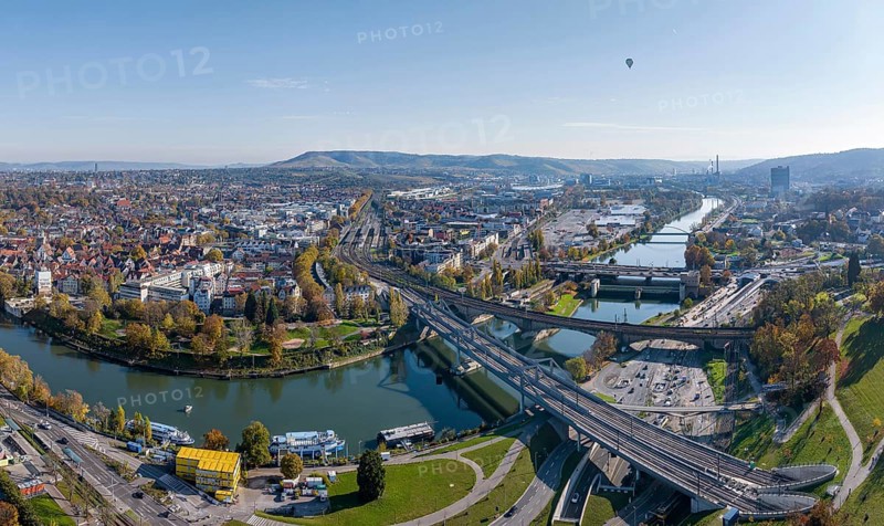 Stuttgart and the Neckar valley, with the Bad Cannstatt district and railway station on the left. In the centre of the picture the Wasen, above it the headquarters of Mercedes-Benz Group AG, the Mercedes Museum and the MHP Arena. Railway bridges over the Neckar. Aerial view, panoramic photo. Stuttgart, Baden-Württemberg, Germany, Europe