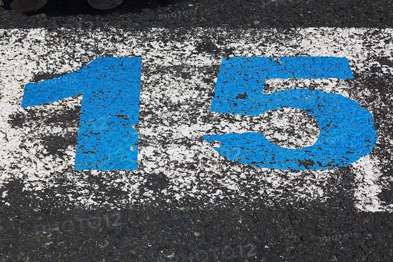 High angle view and close-up of big blue painted number 15 on white painted rectangular background on black paved asphalt surface, Port of Zadar, Croatia, Europe
