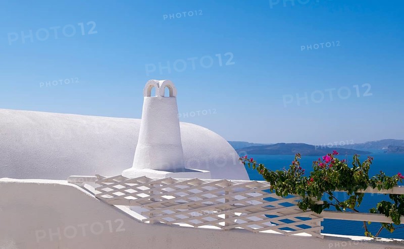 White building with traditional architecture in front of the blue sea and sky, surrounded by flowering plants, Oia, Santorini, Cyclades, Greece, Europe