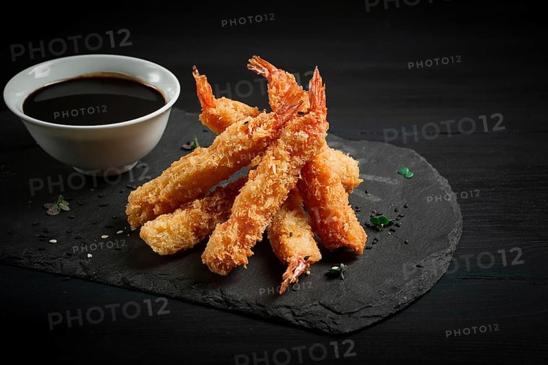 Shrimp in tempura, deep-fried, on black slate, with soy sauce, horizontal, no people