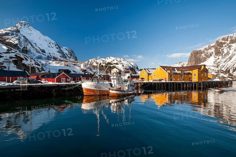 Fishing village with yellow and red houses in front of snow-covered mountains, Nusfjord, Flakstadoya or Flakstadøy, Vestvågøya island, Lofoten, Norway, Europe