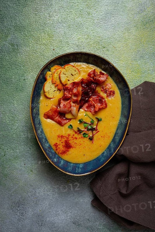 Pumpkin cream soup, curry, fried bacon, bruschetta chips, micro-greens, top view, no people