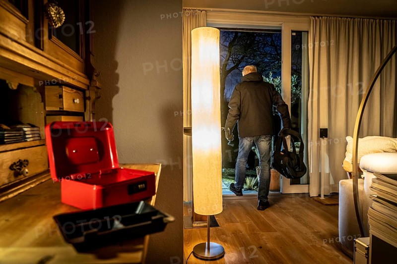 Symbolic image of a burglary, perpetrator has broken into a flat from the garden side and has broken open a cash box, finds valuables, money, leaves the house