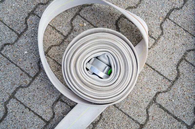 Coiled fire hose with metal buckle on paved ground, fire brigade, Enzklösterle, Black Forest, Germany, Europe