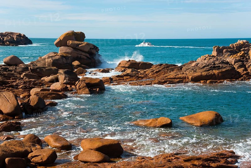 Boat navigating between majestic rocks on a calm coast, Ploumanac'h, Ploumanach, Perros-Guirec, Côtes-d'Armor, Brittany, France, Europe