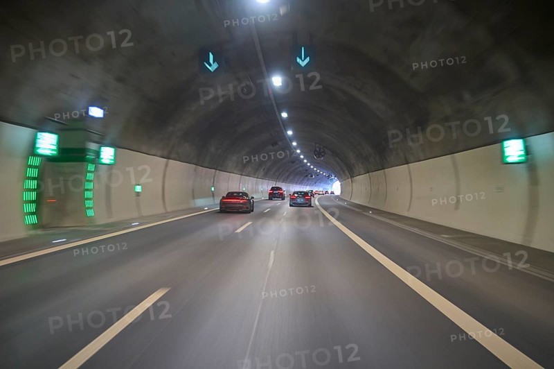Cars drive through an illuminated concrete tunnel under shining lights, Switzerland, Europe