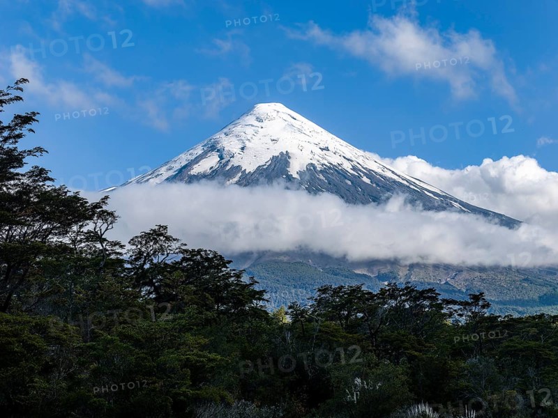 Clouds and forests on the snow-covered Osorno volcano, Chile, South America
