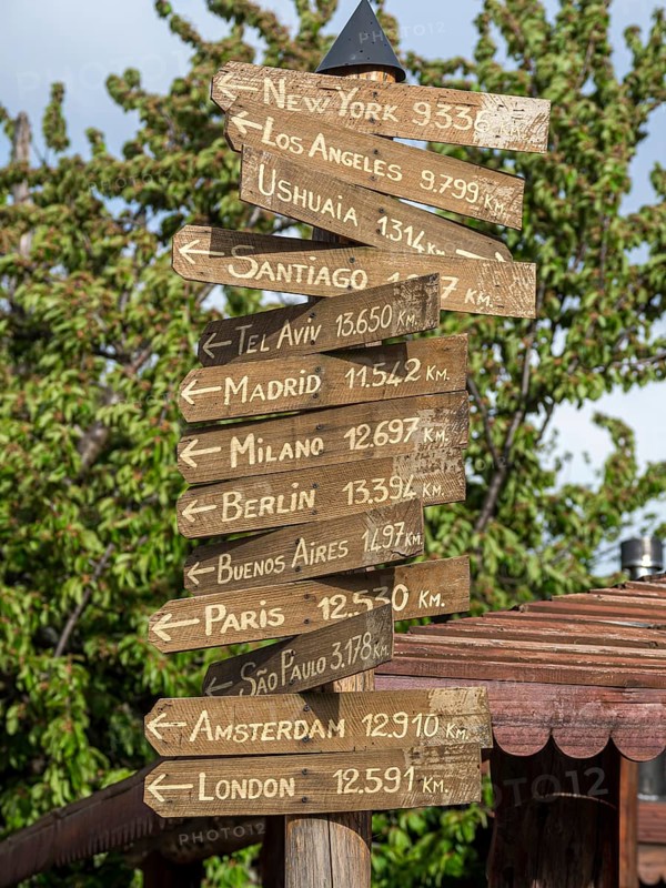 Signpost showing directions to major world cities, Plaza del Arma, Futaleufu, Chile, South America