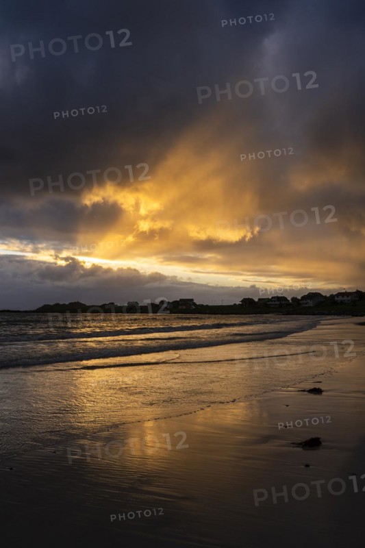 Landscape on the Lofoten Islands. The village of Ramberg, with the sea and the sandy beach (Rambergstranda) in front of it. Dramatic sky with clouds and sunbeams. Reflection. At night at the time of the midnight sun. Early summer. Ramberg, Flakstadoya, Lofoten, Norway, Europe