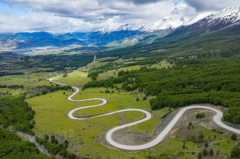 Road Carretera Austral winding down into the valley of Villa Cerro Castillo, snowcapped mountains in early spring, Patagonia, Chile, South America