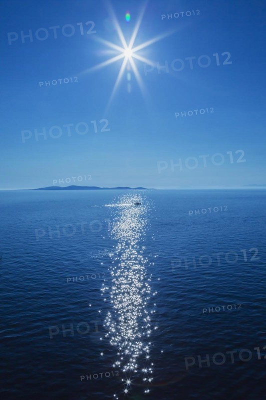 Midday sun over Mediterranean sea with small boat and landmass in the background, Rhodes, Greece, Europe