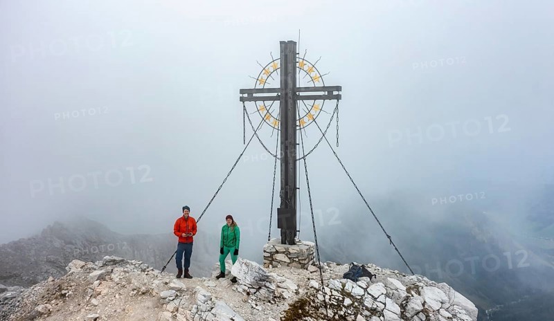 Mountaineer on the summit of the Großer Kinigat with summit cross, Carnic Main Ridge, Carnic High Trail, Carnic Alps, Carinthia, Austria, Europe