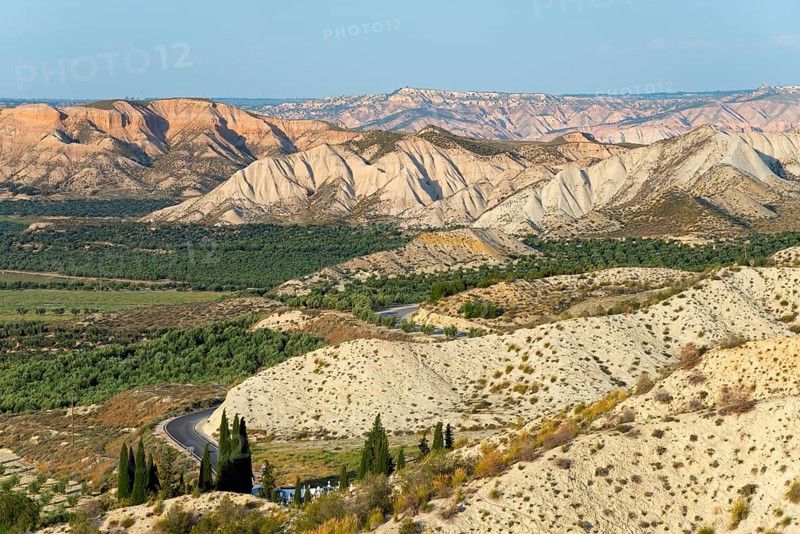 Wide desert landscape with rocky hills and serpentine road under a blue sky, Dehesas de Guadix, Gorafe Desert, Granada, Andalusia, Spain, Europe