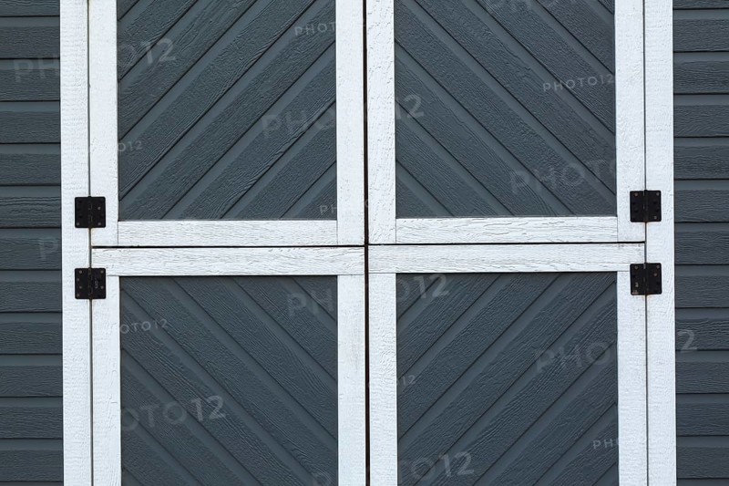 Individual small square doors on storage shed cladded with grey and white trim canexel wood composite clapboard, Quebec, Canada, North America