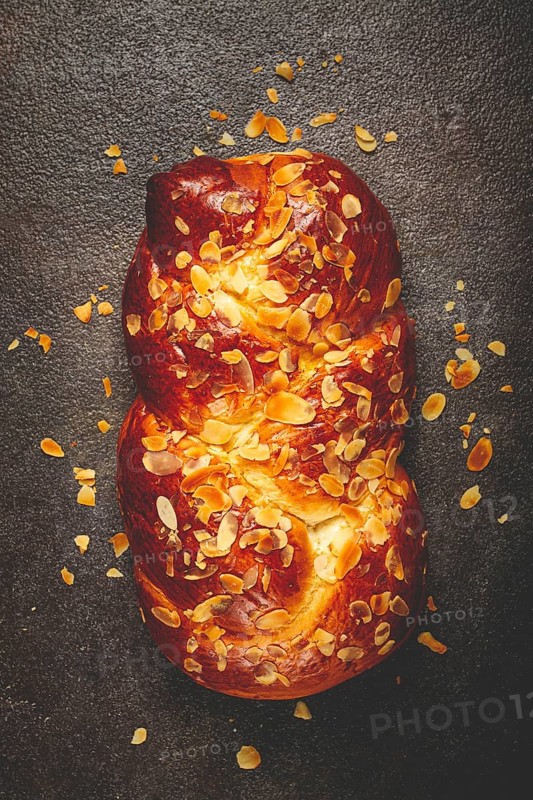 Braided, sweet bread pie, with sliced almonds, breakfast, braided bread, brioche, on a dark background, top view, no people
