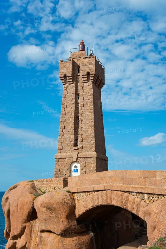 Lighthouse above an arch of rocks in front of a blue sky with clouds, Phare de Men Ruz, Ploumanac'h, Ploumanach, Pointe de Squewel, Perros-Guirec, pink granite coast, Côte de Granit Rose, Brittany, France, Europe