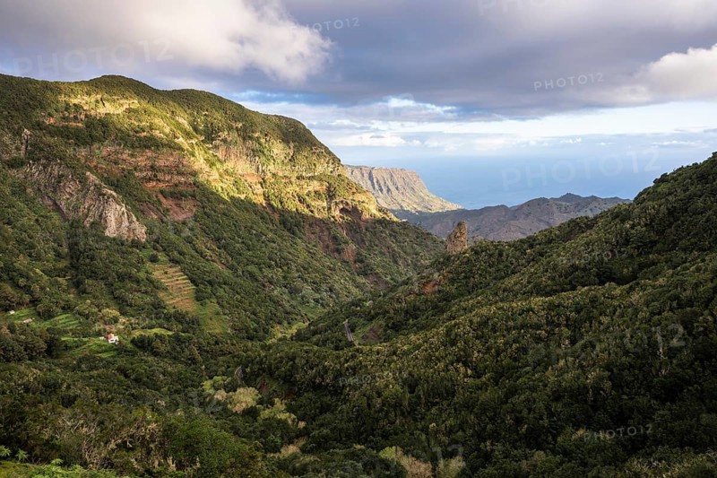 View of the valley of Hermigua and the sea. Mountains, hillsides with forest, palm trees, rocks. Good weather. La Gomera, Canary Islands, Spain, Europe