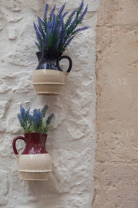 Jugs with artificial flowers hanging as decoration on a white house wall, Cisternino, southern Italy, Italy, Europe