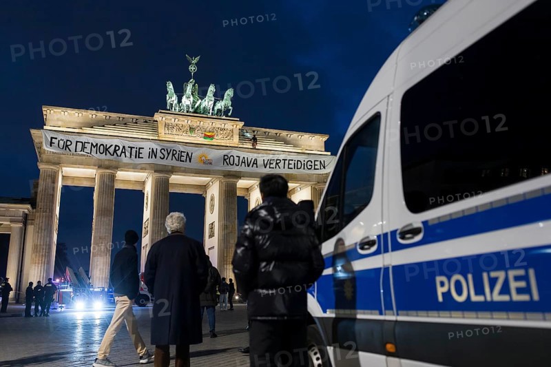 A banner For Democracy in Syria / Defend Rojava hangs at the Brandenburg Tor, Berlin, 16 December 2024