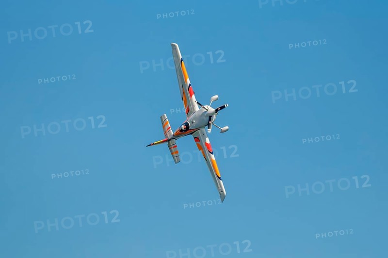 Stunt aerobatic plane performing stunts in blue sky. Concept of speed, difficulty, precision, risk, challenge