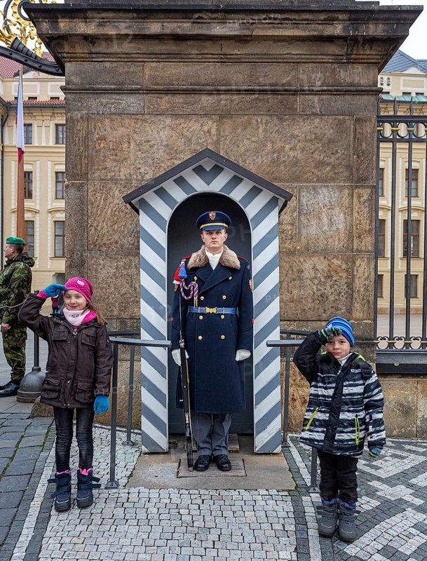 Two children salute next to the castle guard, Prague, Czech Republic, Europe