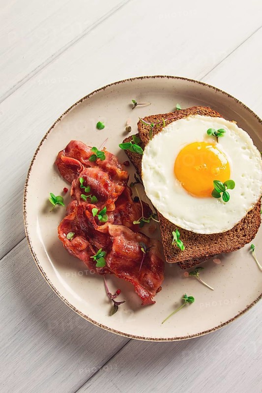 Breakfast, fried egg with bacon, micro-green, on a light background, no people, selective focus