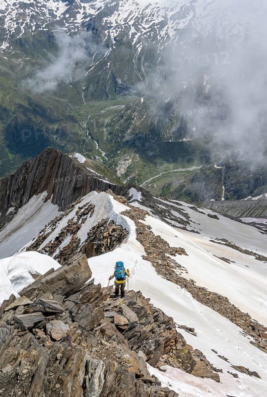 Mountaineer on a rocky ridge with snow, descent from the summit of the Schönbichler Horn, view of Tal Zemmgrund, Berliner Höhenweg, Zillertal Alps, Tyrol, Austria, Europe