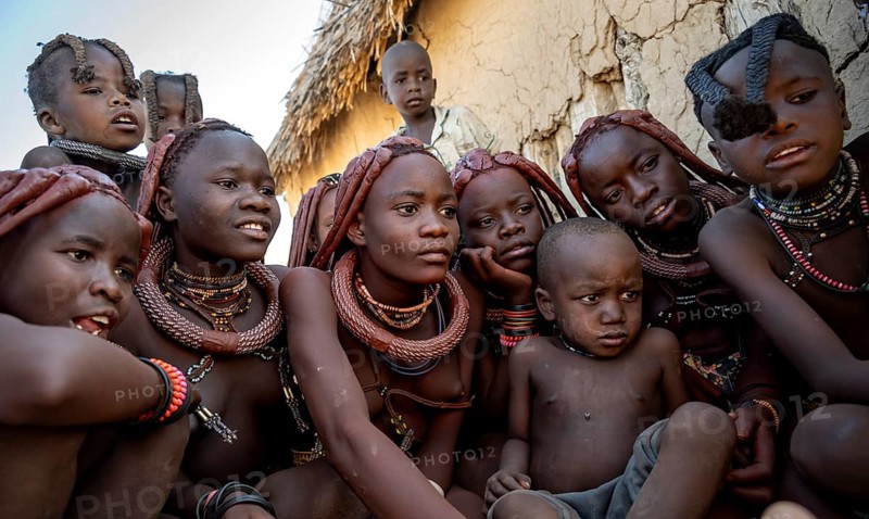 Group of Himba children and young woman look at pictures on a camera, near Opuwo, Kaokoveld, Kunene, Namibia, Africa