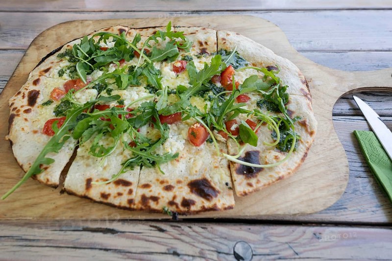 Original tarte flambée with bacon and rocket served on a wooden board in a garden restaurant, Baden-Württemberg, Germany, Europe