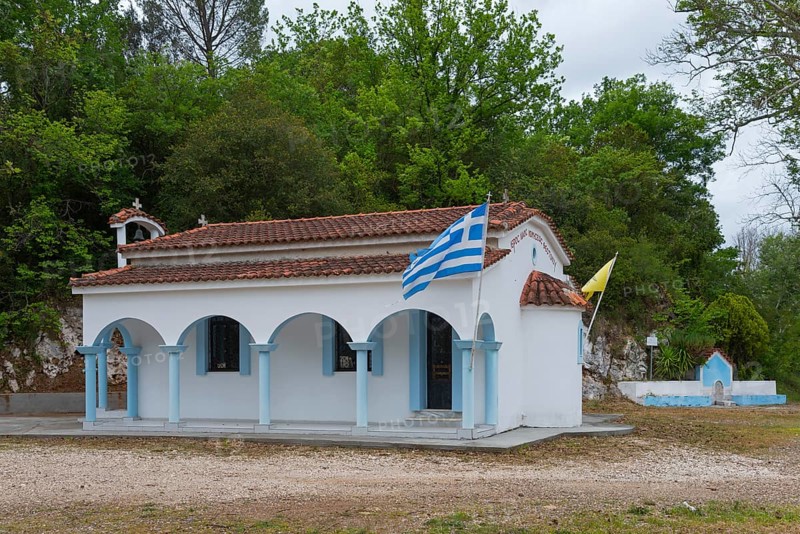 Small Greek church in a rural setting with flags and surrounding trees, located on the 77, island of Euboea, Central Greece, Greece, Europe
