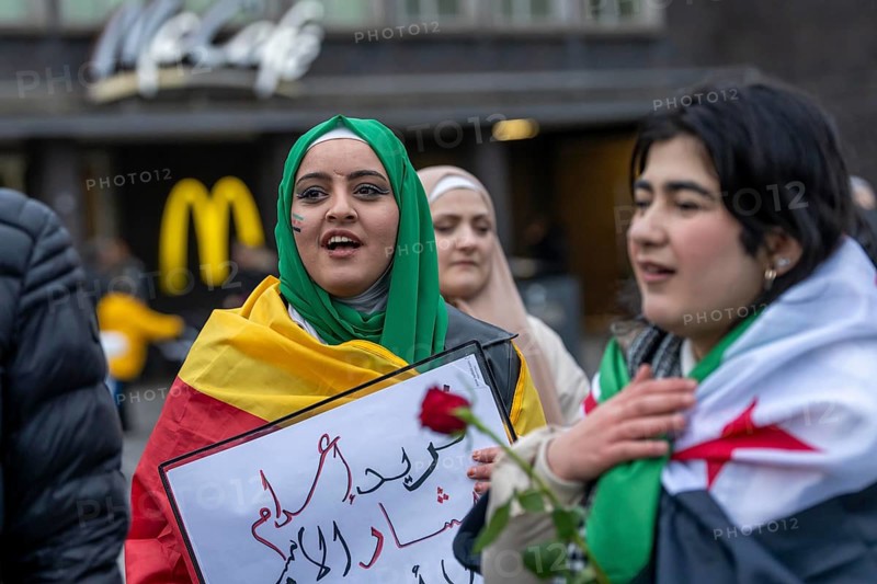 Syrian woman celebrate the end of the Assad regime after the change of power in Syria at a rally on the square in front of the main railway station in Duisburg, North Rhine-Westphalia, Germany, Europe