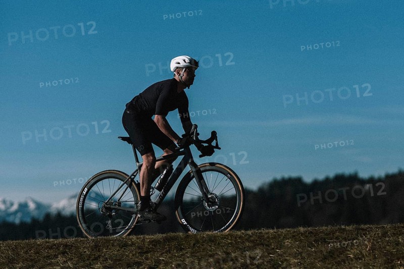 Road bike rider in spring near Halblech in the Allgäu in front of a picturesque backdrop of the Alps, Bavaria, Germany, Europe