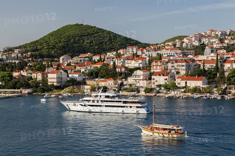 Suzana Zantium private yacht and sightseeing boat plus tan and white trim houses and villas with traditional terracotta clay tile rooftops on hillside on Lapad peninsula in late summer, Dubrovnik, Croatia, Europe