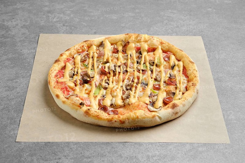 Pizza with thin sausage, jalapeno and champignon covered with mustard on parchment paper