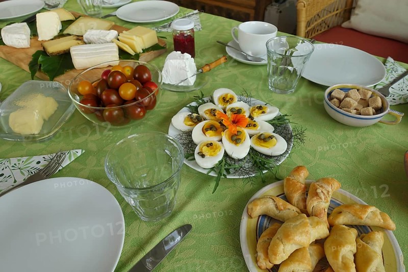 Breakfast table, breakfast, cold buffet, tomatoes in glass bowl, cheese board, wooden board, sliced eggs, hard eggs with capers on plate, dill, rocket, rocket, decoration, flower nasturtium, ham croissant, crockery, plates, cups, cutlery, glasses, butter plate, butter dish, jam in glass, food, food and drink, studio, Germany, Europe