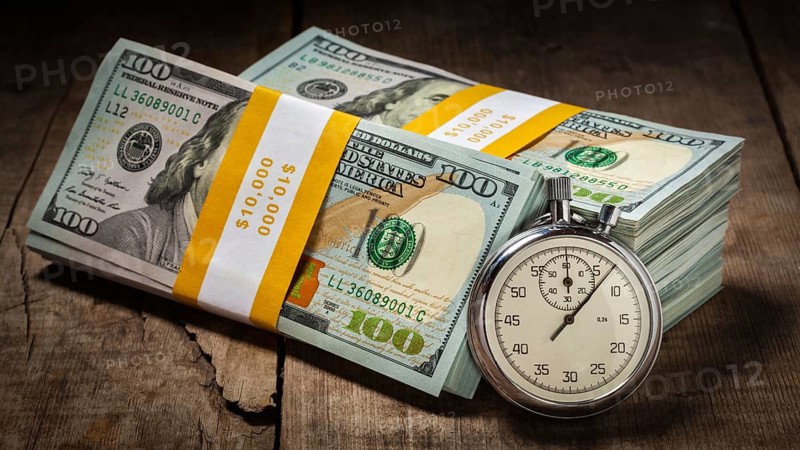 Time is money loan concept background, panorama of stopwatch and stack of new 100 US dollars 2013 edition banknotes (bills) bundles on wooden background
