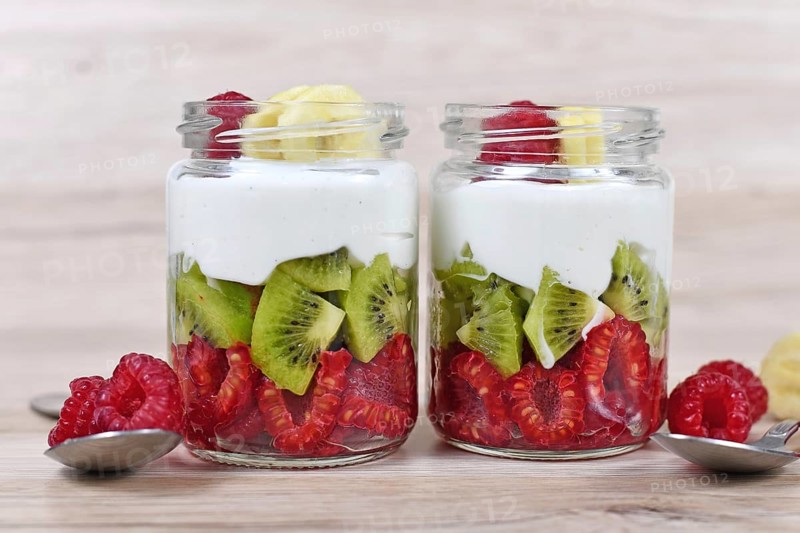 Healthy snack with raw raspberry and kiwi fruits and yoghurt layered in glass