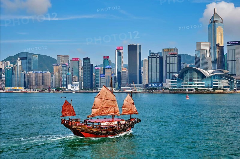 HONG KONG, CHINA, MAY 1, 2018: Hong Kong skyline cityscape downtown skyscrapers over Victoria Harbour with tourist junk boat on sunset. Hong Kong, China, Asia