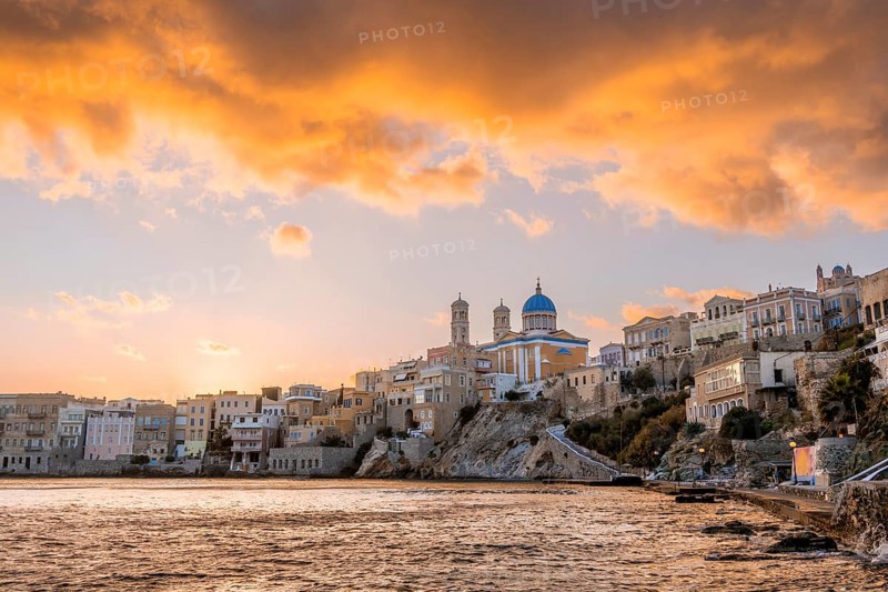 View of the village with the Greek Orthodox church of Agios Nikolaos, Asteria Beach, at sunset with atmospheric clouds, Ermoupoli, Syros, Cyclades, Greece, Europe