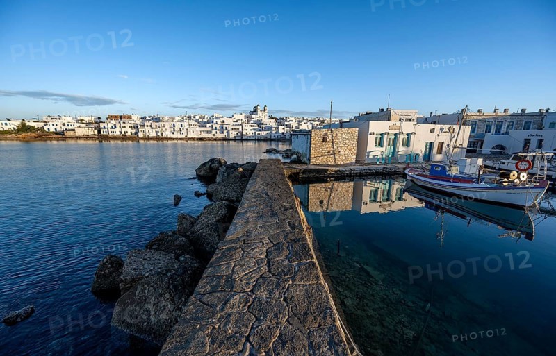 Harbour wall, local view of Naoussa town and blue sea, harbour with fishing boats and reflection, white Cycladic houses and church Agios Faneromeni, Paros, Cyclades, Greece, Europe