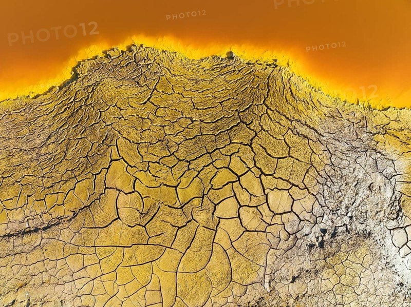 Cracked earth at the bank of the Rio Tinto (Red river) with its deep reddish hue due to oxidised iron minerals in its water, aerial view, drone shot, Huelva province, Andalusia, Spain, Europe