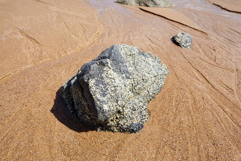 Stones in receding water at low tide on the beach at Plévenon, Côtes-d'Armor, Brittany, France, Europe