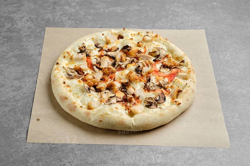 Pizza with chicken breast and champignon mushrooms on parchment paper