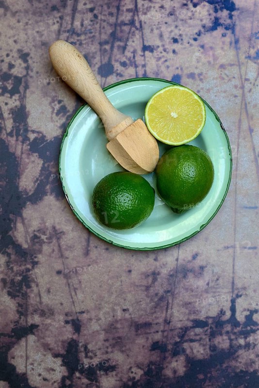 Limes with citrus squeezer on plate