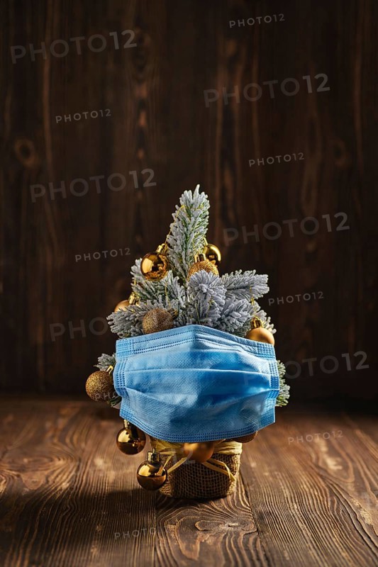 Christmas tree with surgical or medical mask on wooden background