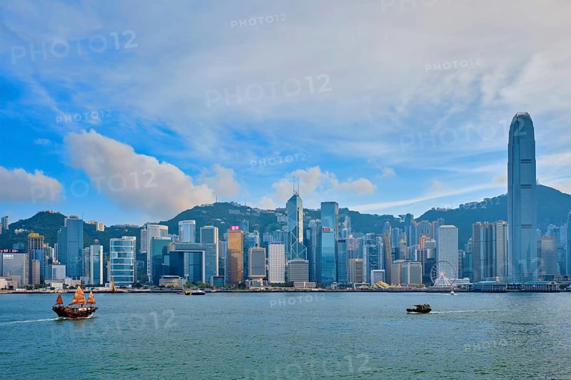 HONG KONG, CHINA, MAY 1, 2018: Hong Kong skyline cityscape downtown skyscrapers over Victoria Harbour with tourist junk boat on sunset. Hong Kong, China, Asia