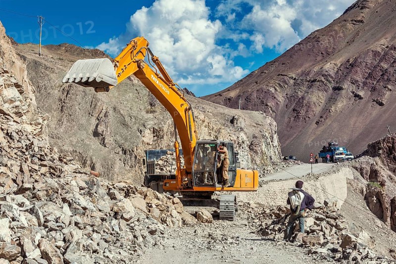 LADAKH, INDIA, SEPTEMBER 10, 2011: Excavator cleaning road after landslide in Himalayas. Ladakh, Jammu and Kashmir, India, Asia