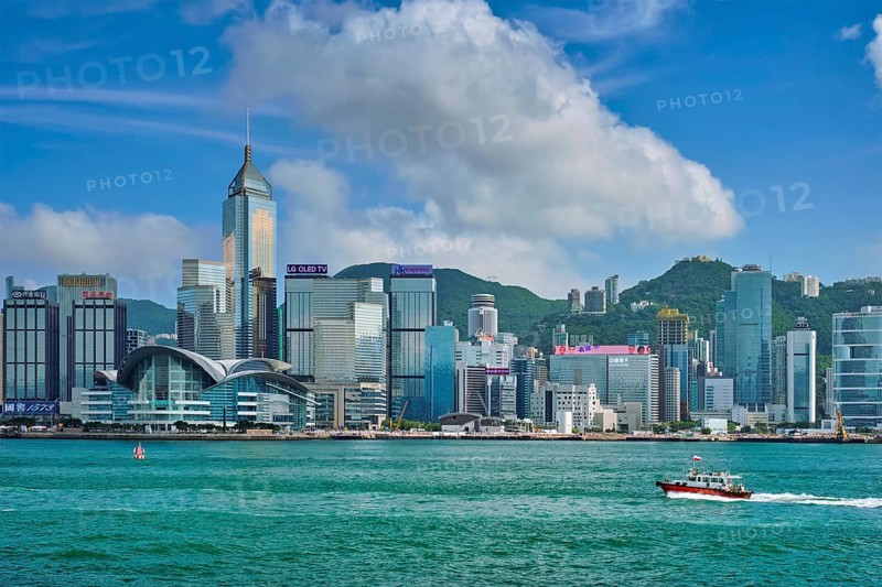 HONG KONG, CHINA, MAY 1, 2018: Boat in Victoria Harbour and Hong Kong skyline cityscape downtown skyscrapers over in the day time with clouds. Hong Kong, China, Asia