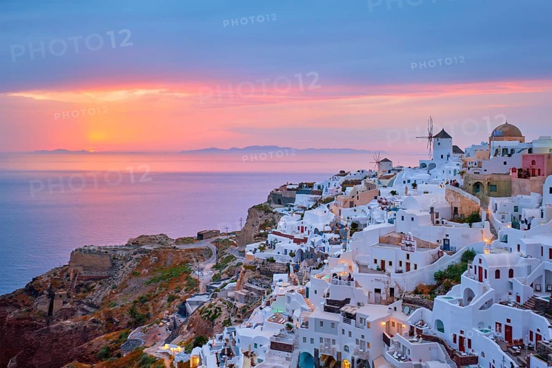 Famous greek iconic selfie spot tourist destination Oia village with traditional white houses and windmills in Santorini island on sunset in twilight, Greece, Europe