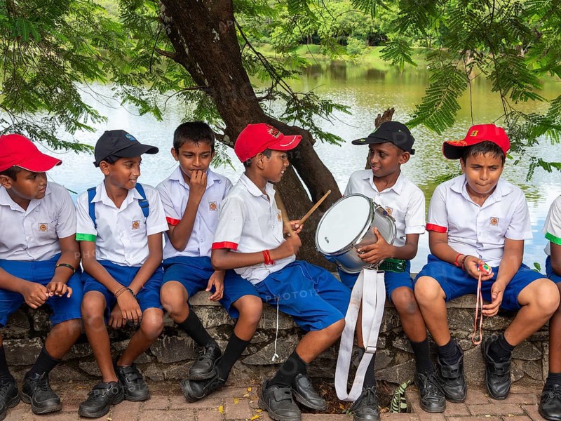 School children school uniform sitting on wall and drumming, Sri Lanka, Asia